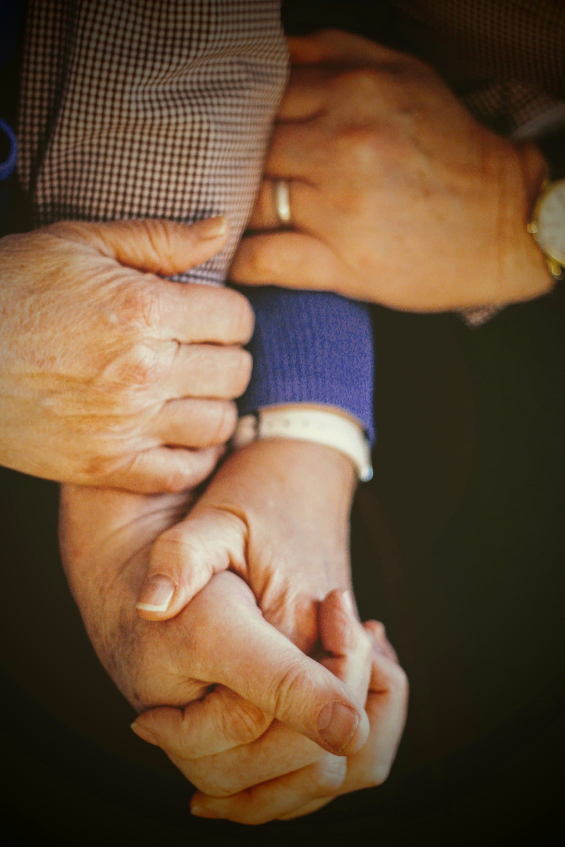 Three pairs of hands from different generations resting on one another.